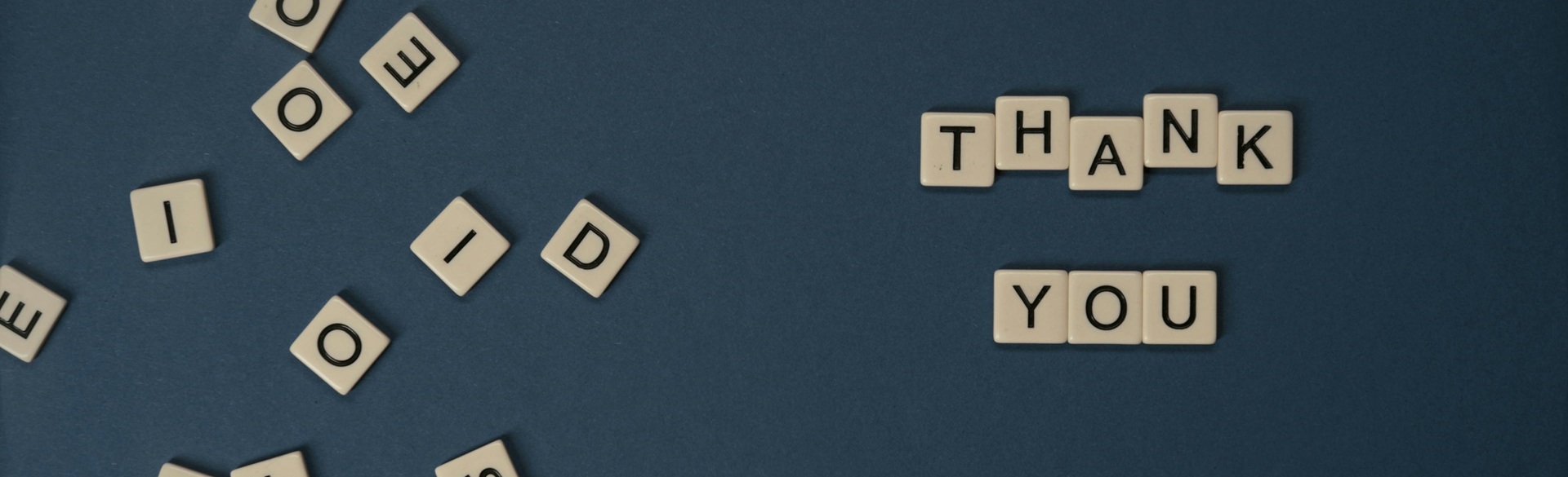 Letter tiles spelling 'Thank you' on a dark blue background